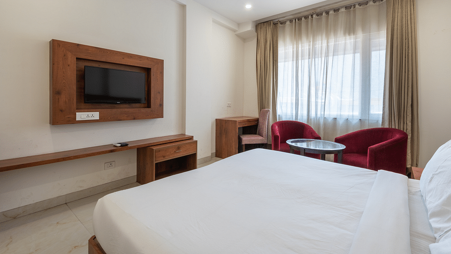 Club balcony room featuring a comfortable bed, wall-mounted TV, and a balcony partially covered by sheer curtains at DLS The Classio